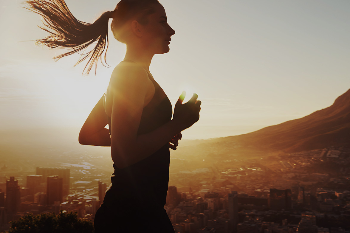 Woman running against a sundrenched urban skyline